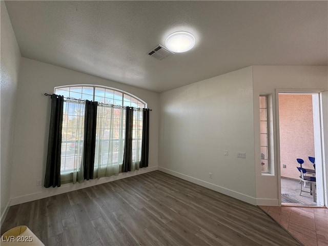 empty room featuring dark wood-type flooring and a textured ceiling