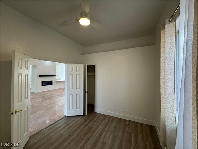 unfurnished room featuring dark hardwood / wood-style floors, vaulted ceiling, and ceiling fan