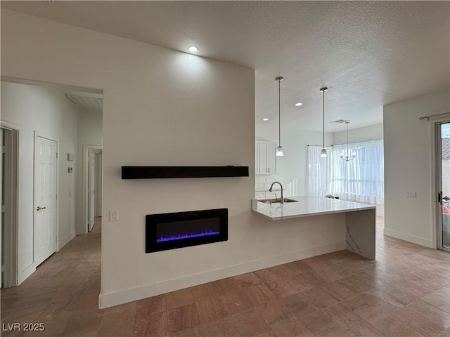 kitchen featuring kitchen peninsula, sink, decorative light fixtures, an inviting chandelier, and white cabinets