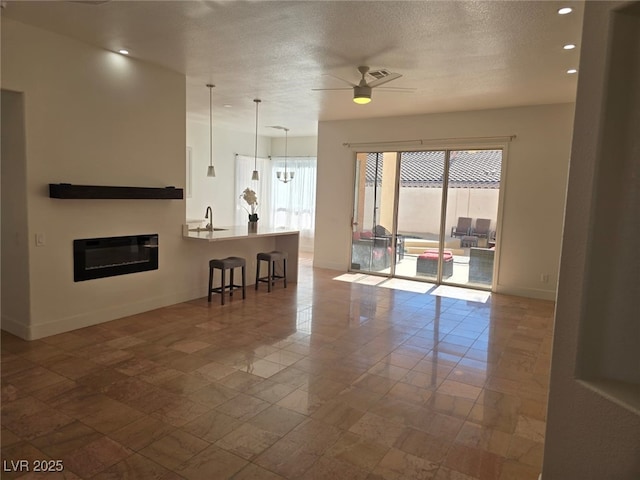 living room featuring a textured ceiling, plenty of natural light, ceiling fan, and sink