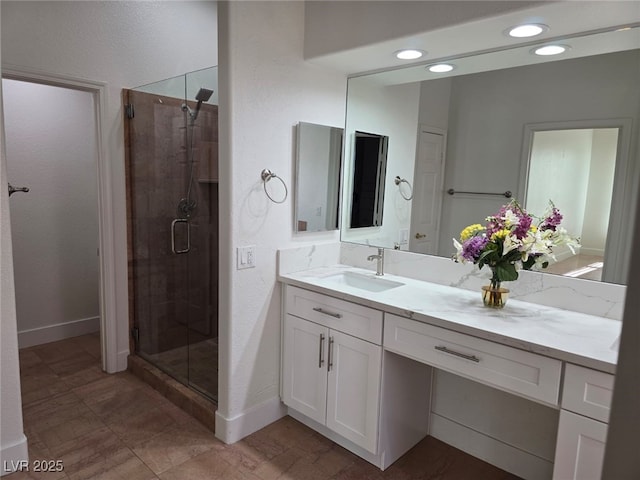 bathroom featuring a shower with door and vanity