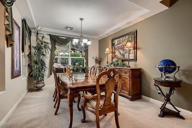 carpeted dining area with a tray ceiling and a notable chandelier