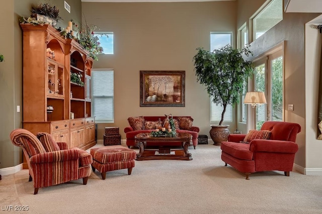 carpeted living room with a high ceiling and a healthy amount of sunlight