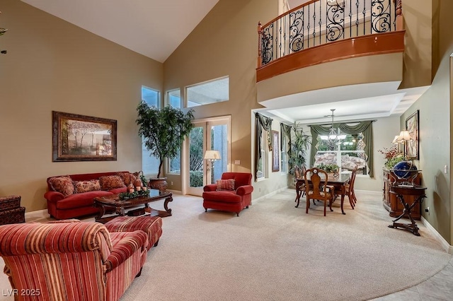 living room with carpet floors, a towering ceiling, and an inviting chandelier