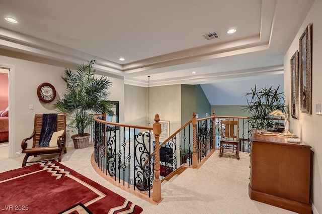 hallway with a tray ceiling and light colored carpet