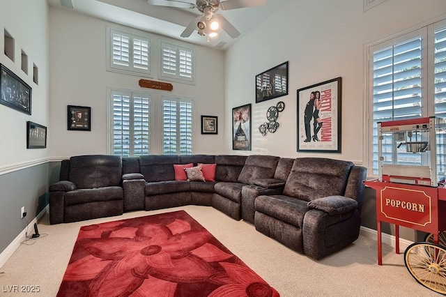 carpeted living room featuring a towering ceiling and ceiling fan