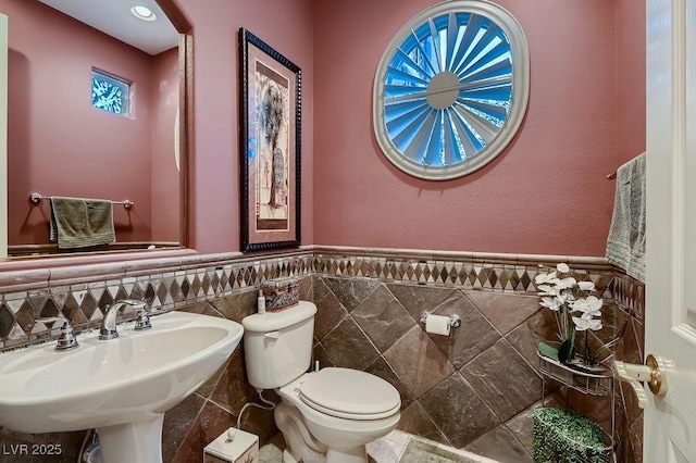 bathroom with tile walls, sink, and toilet