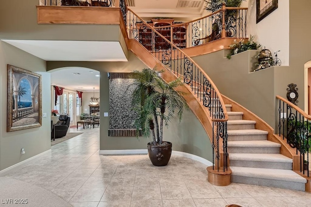 stairway with a towering ceiling and tile patterned floors