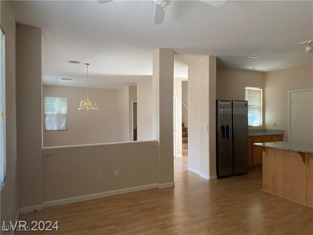 kitchen featuring light hardwood / wood-style flooring, stainless steel fridge, a chandelier, decorative light fixtures, and a breakfast bar area