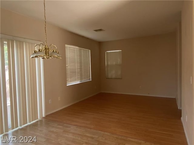 empty room with an inviting chandelier and hardwood / wood-style flooring