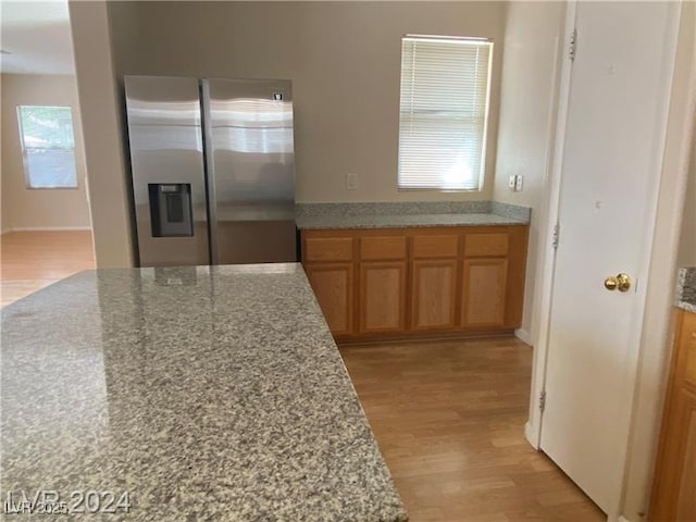 kitchen with stainless steel fridge with ice dispenser and light wood-type flooring