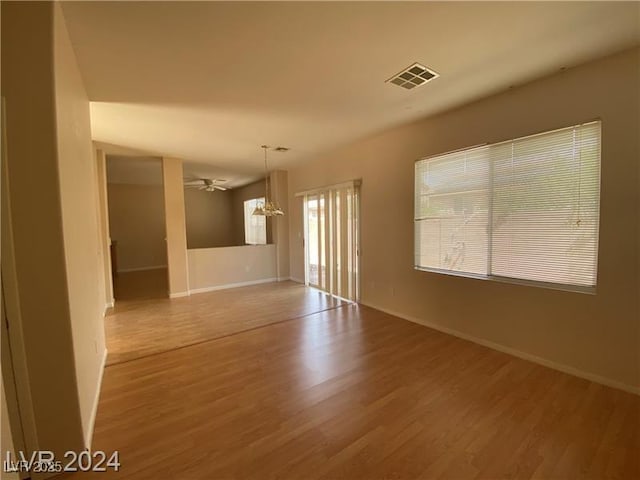 empty room with hardwood / wood-style floors and ceiling fan with notable chandelier