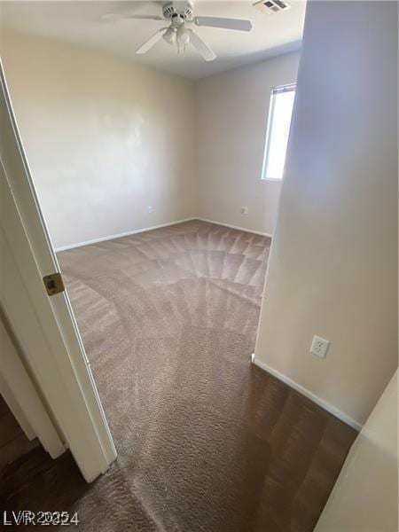 spare room with ceiling fan and dark carpet