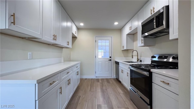 kitchen featuring white cabinetry, sink, stainless steel appliances, and light hardwood / wood-style floors