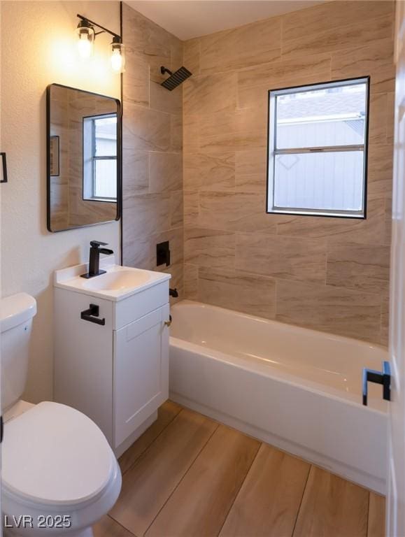 full bathroom featuring vanity, tiled shower / bath combo, and toilet