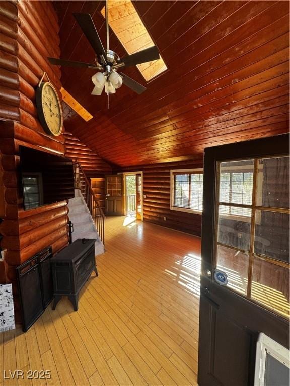 unfurnished living room with lofted ceiling, wooden ceiling, light hardwood / wood-style flooring, ceiling fan, and rustic walls