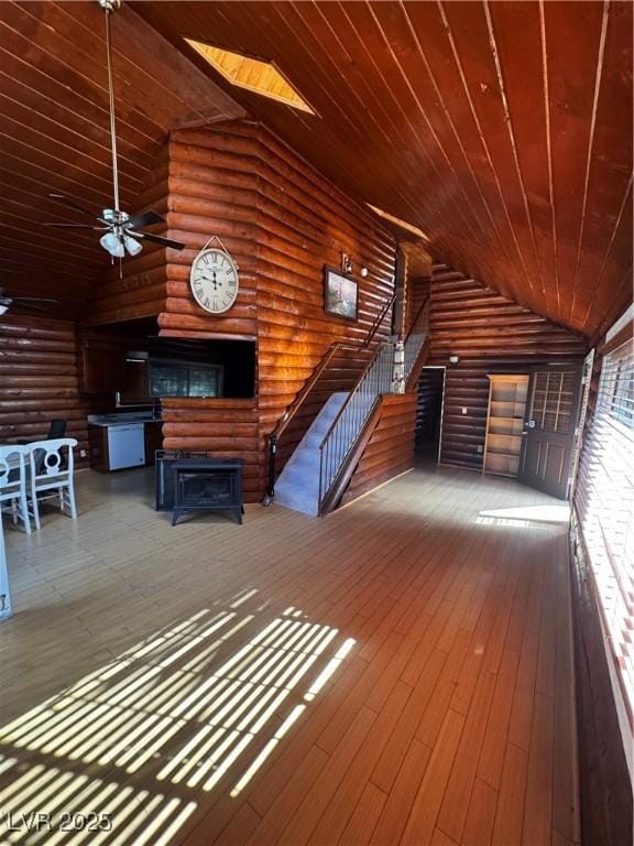 unfurnished living room with rustic walls, ceiling fan, wood ceiling, and vaulted ceiling