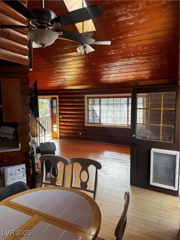 dining area with ceiling fan, plenty of natural light, log walls, and hardwood / wood-style floors