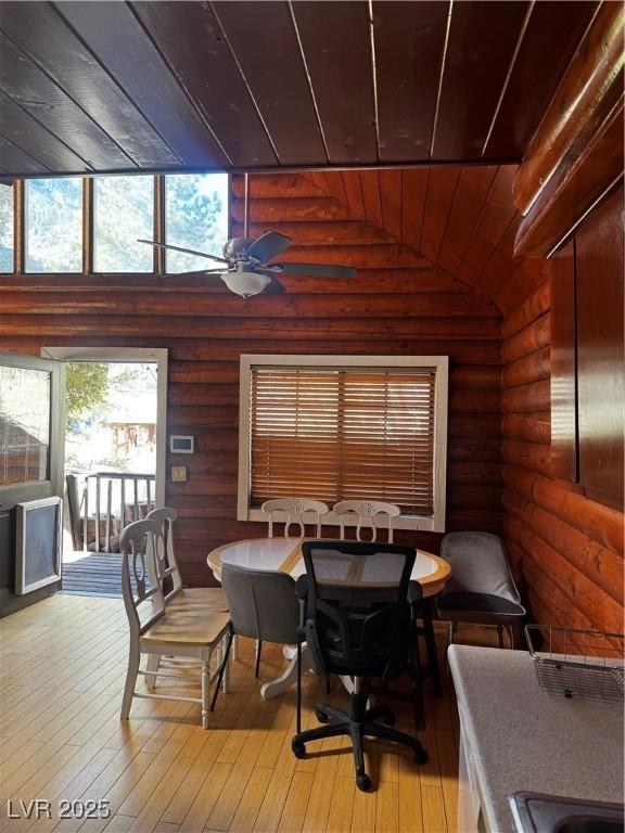 dining room with rustic walls, wood ceiling, ceiling fan, hardwood / wood-style floors, and lofted ceiling