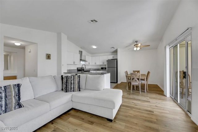 living room with ceiling fan, light wood-type flooring, and sink