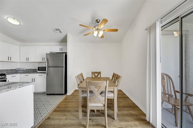 kitchen featuring white cabinetry, light hardwood / wood-style flooring, light stone countertops, and appliances with stainless steel finishes