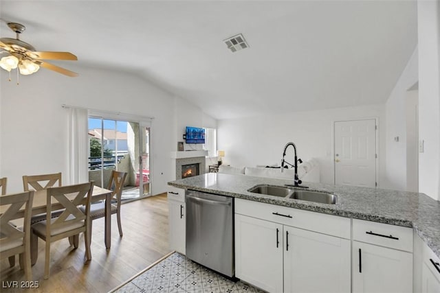 kitchen with light stone countertops, stainless steel dishwasher, ceiling fan, sink, and white cabinets