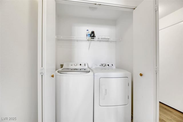 clothes washing area with light hardwood / wood-style flooring and washer and dryer