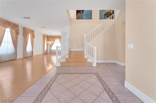 entryway with light tile patterned flooring and a chandelier