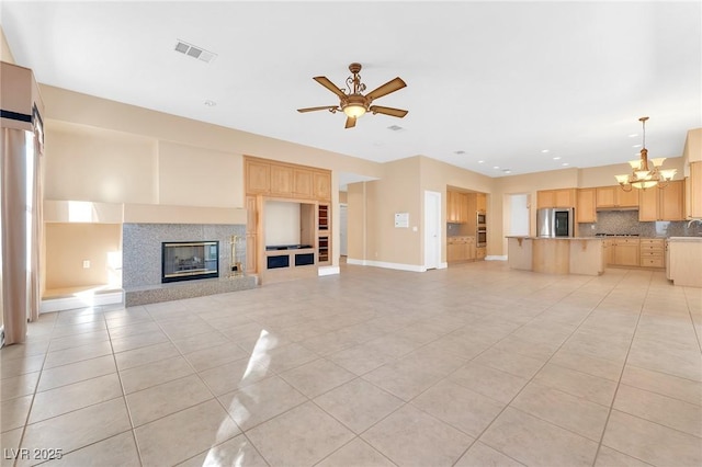 unfurnished living room featuring sink, ceiling fan with notable chandelier, and light tile patterned floors