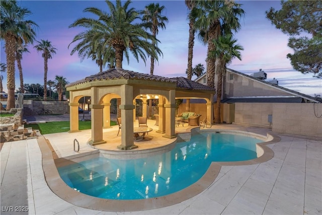 pool at dusk featuring a patio area