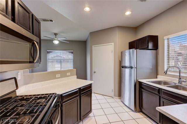 kitchen featuring dark brown cabinetry, ceiling fan, sink, light tile patterned floors, and appliances with stainless steel finishes