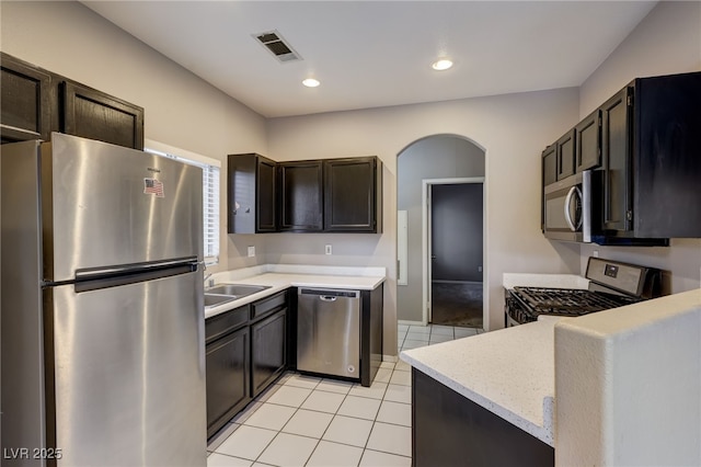 kitchen with light tile patterned flooring, dark brown cabinetry, stainless steel appliances, and sink