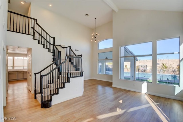 entrance foyer with a chandelier, beamed ceiling, high vaulted ceiling, and wood-type flooring