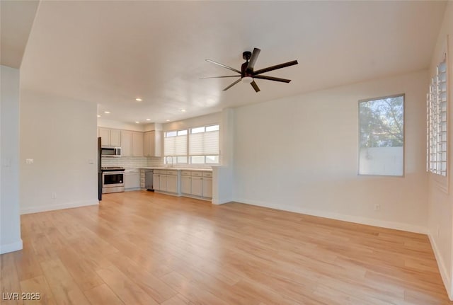 unfurnished living room featuring light hardwood / wood-style floors, ceiling fan, and sink