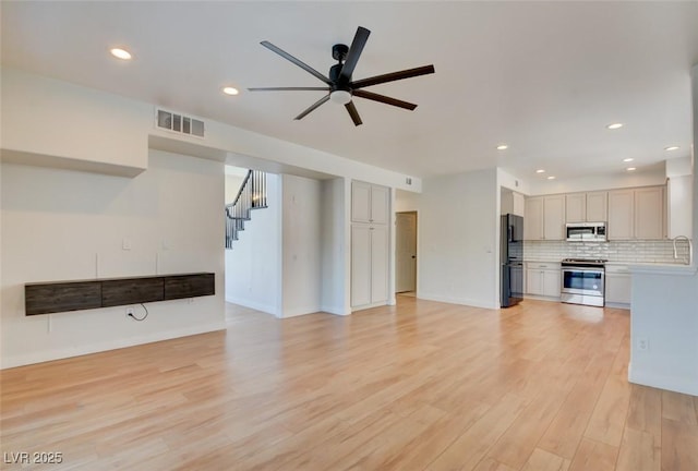 unfurnished living room featuring ceiling fan and light wood-type flooring