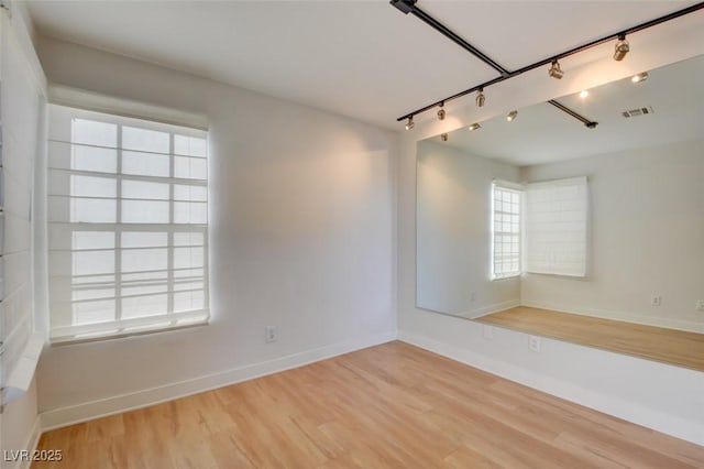 unfurnished room with a healthy amount of sunlight, wood-type flooring, and track lighting