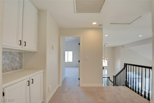 hall featuring light carpet, a chandelier, and vaulted ceiling