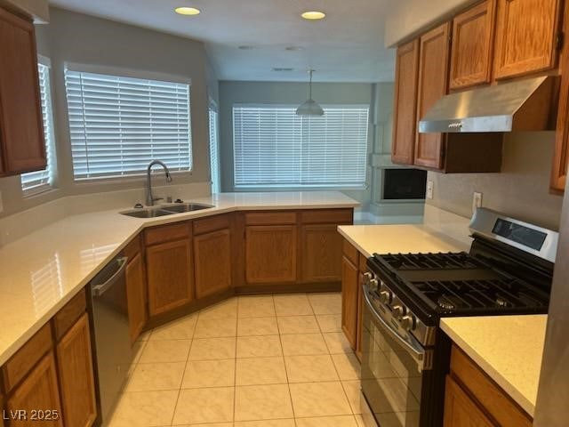 kitchen with light tile patterned flooring, stainless steel appliances, hanging light fixtures, and sink