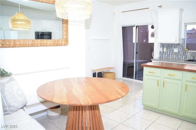 kitchen with butcher block counters, white cabinetry, crown molding, and hanging light fixtures