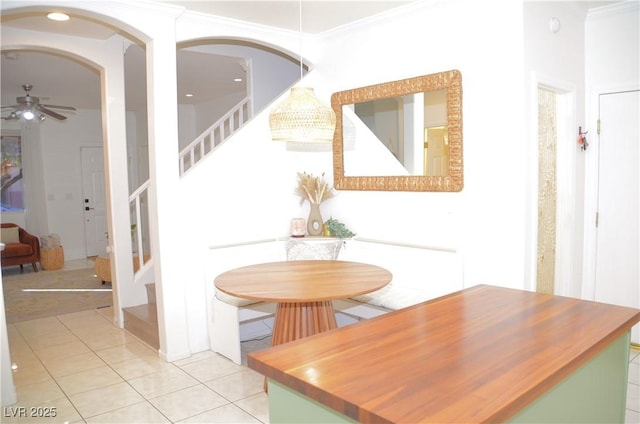 tiled dining area featuring ceiling fan and crown molding