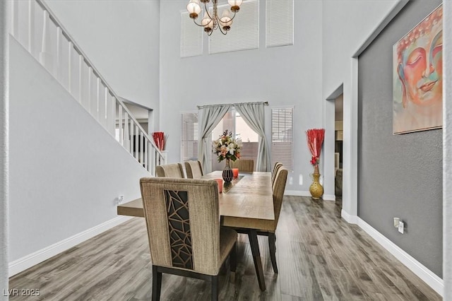 dining room with hardwood / wood-style flooring, a notable chandelier, and a high ceiling