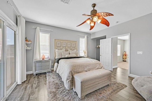 bedroom with hardwood / wood-style flooring, ceiling fan, and multiple windows