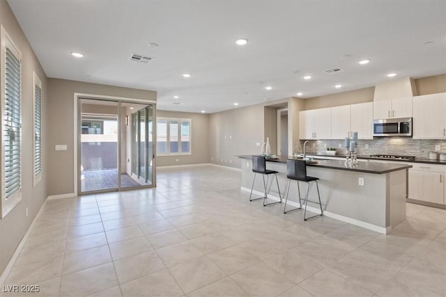 kitchen featuring a kitchen island with sink, sink, tasteful backsplash, and a kitchen breakfast bar