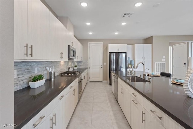 kitchen with sink, backsplash, light tile patterned floors, and appliances with stainless steel finishes