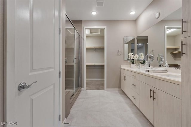 bathroom with a shower with door, vanity, and tile patterned floors