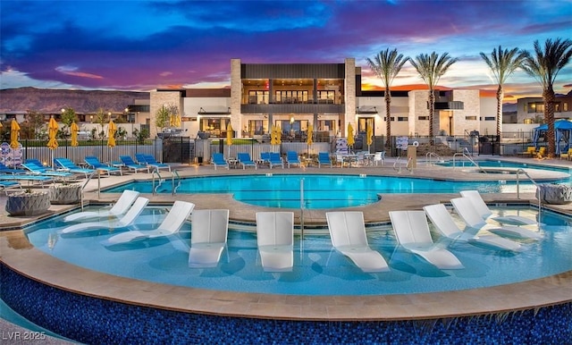 pool at dusk featuring a patio area and a community hot tub