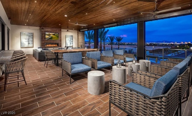 patio terrace at dusk with an outdoor living space with a fireplace and ceiling fan