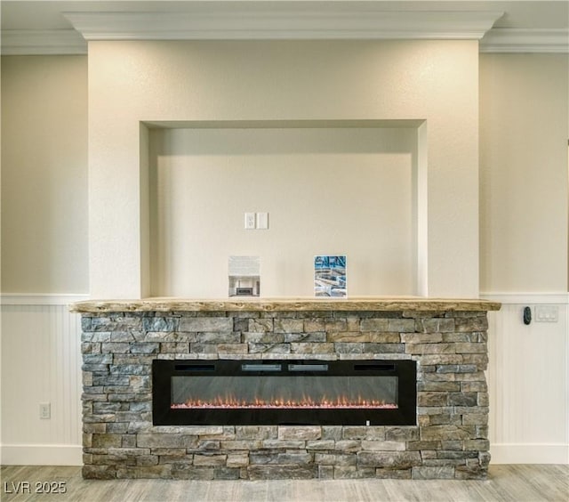 details featuring crown molding, a stone fireplace, and wood-type flooring