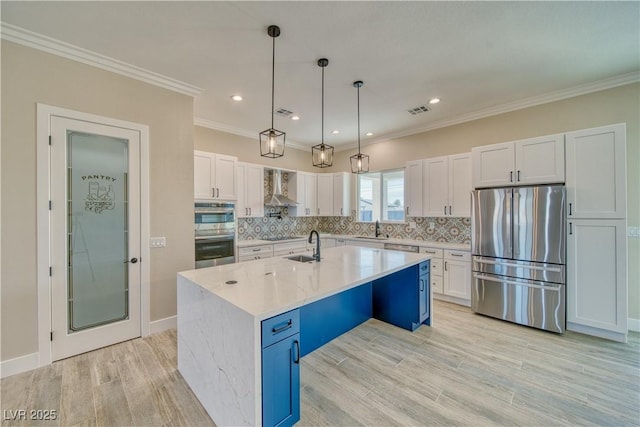 kitchen with white cabinetry, wall chimney range hood, a center island with sink, and appliances with stainless steel finishes