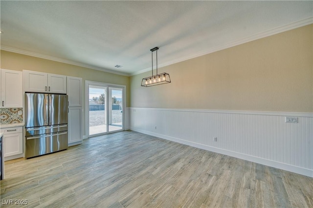 unfurnished dining area featuring ornamental molding and light hardwood / wood-style floors